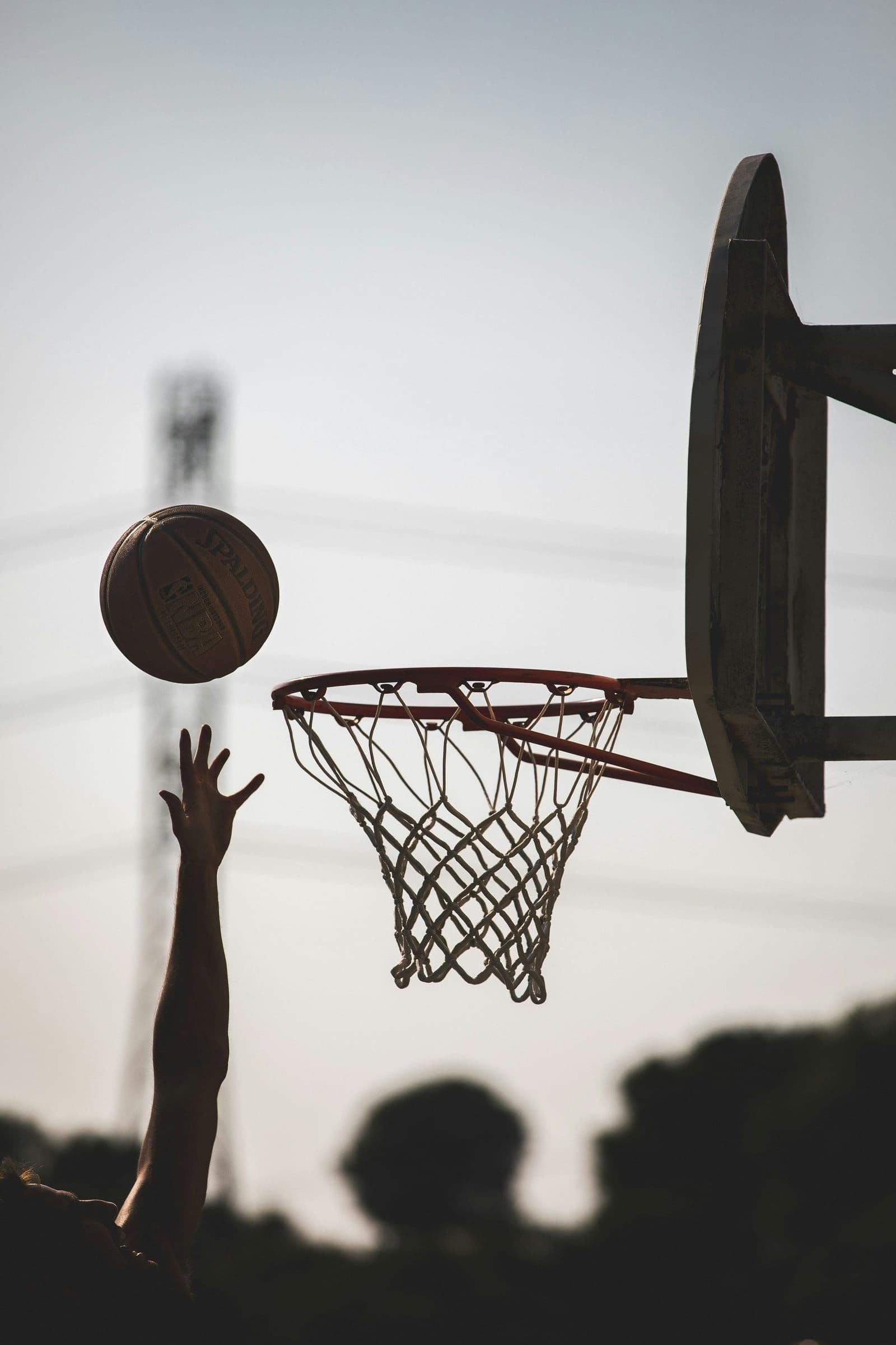 Basketball arcing toward the rim at dusk
