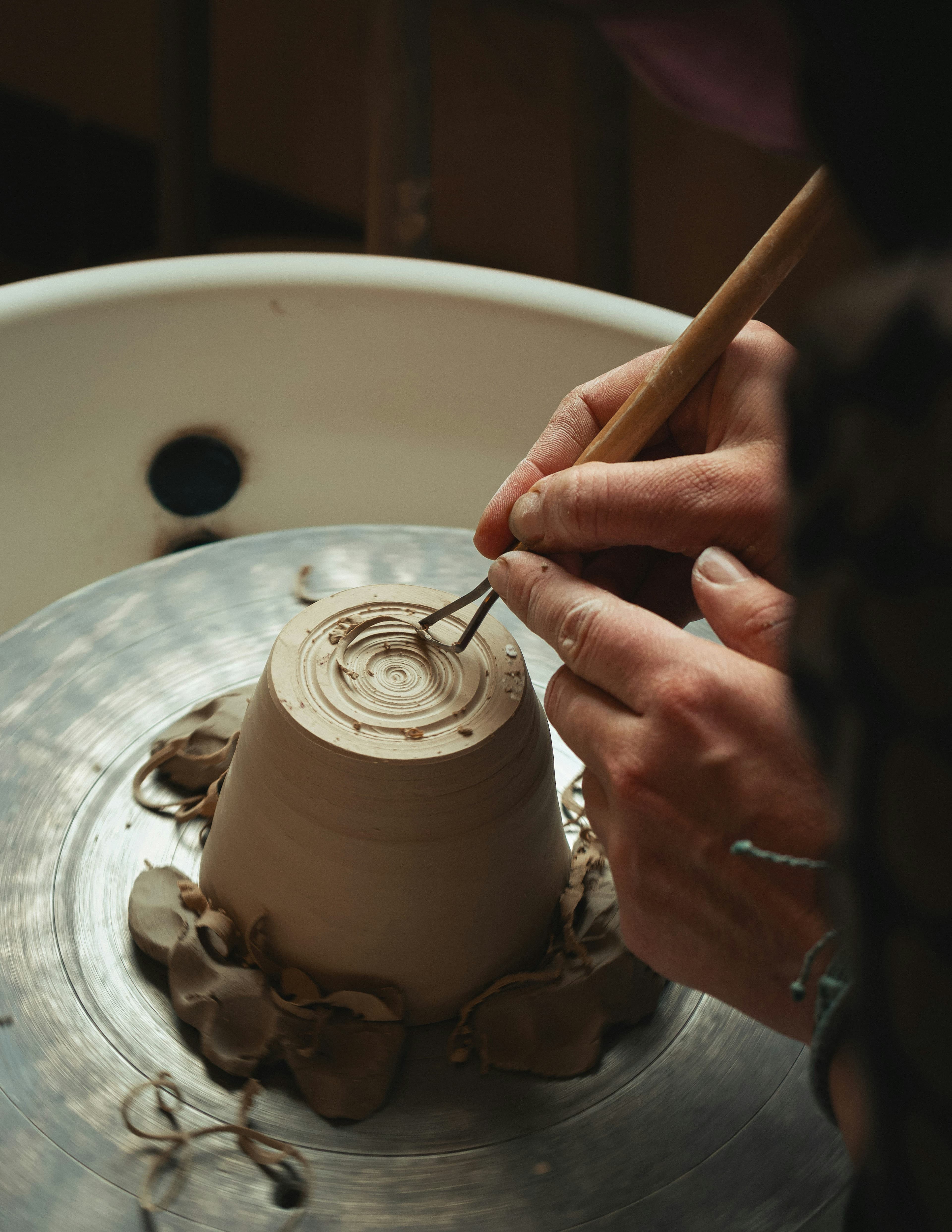 Hands trimming a pot on a pottery wheel