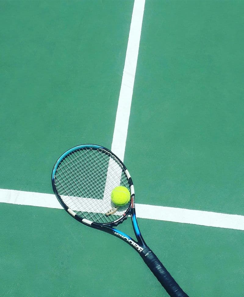 Tennis racket and ball on a green hard court