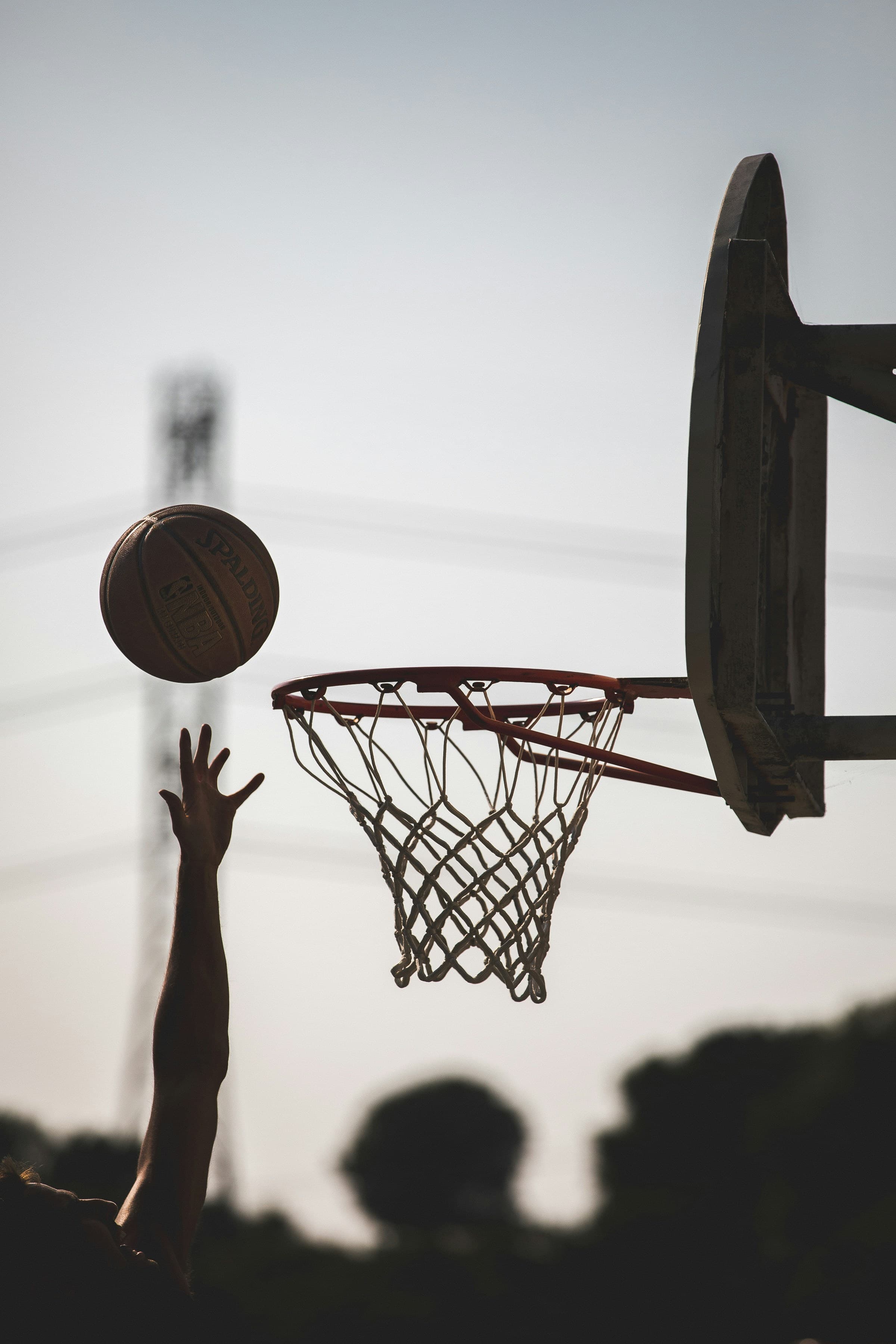 Basketball arcing toward the rim at dusk