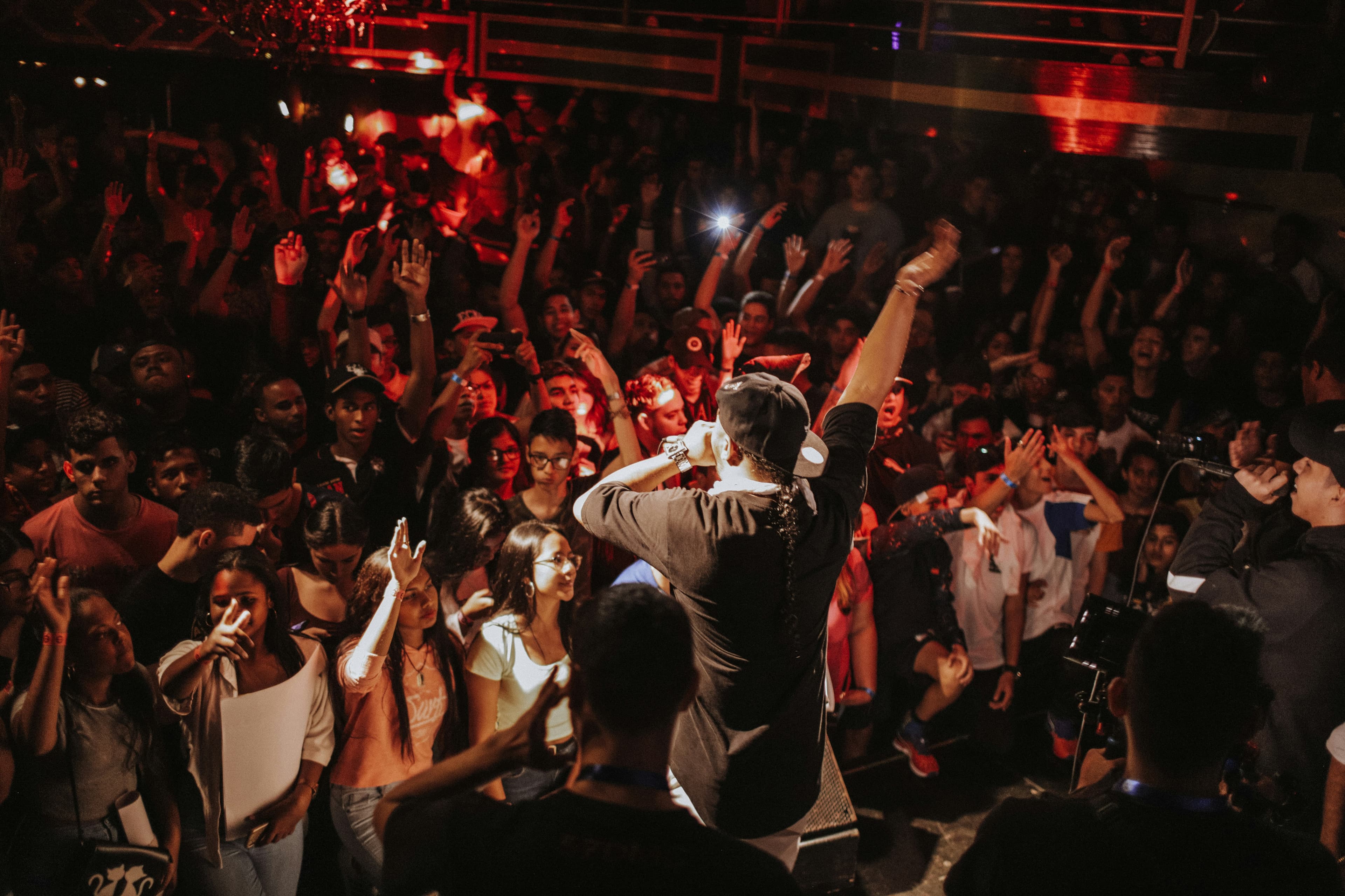 Performer facing a packed crowd with hands raised
